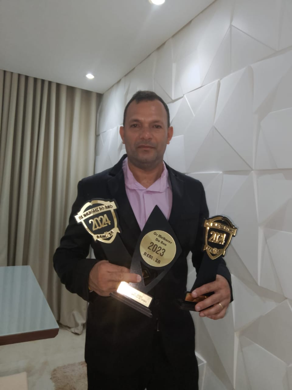 Mário Gesso segurando troféus de reconhecimento